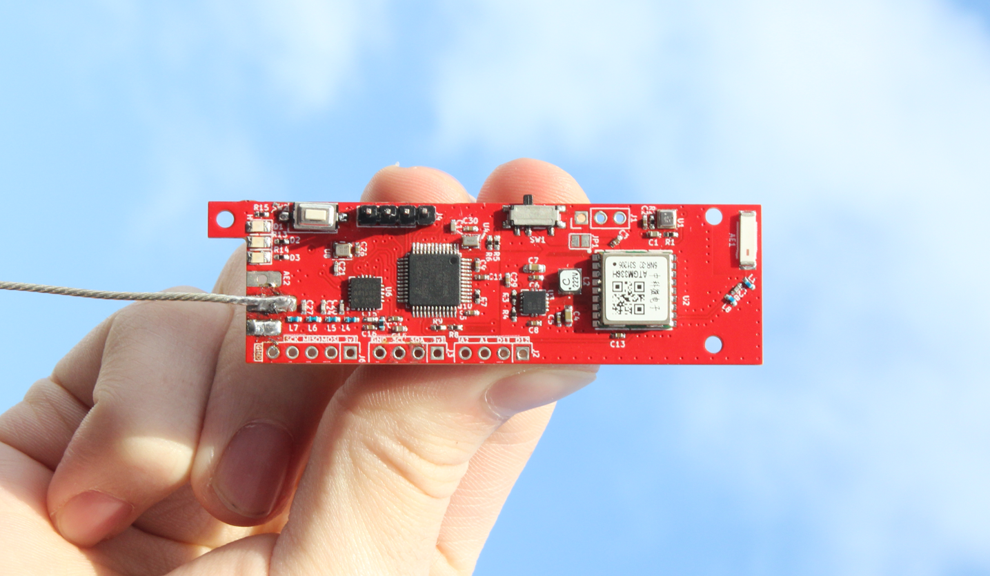 The Tiny4FSK PCB, a red PCB board held against the sky